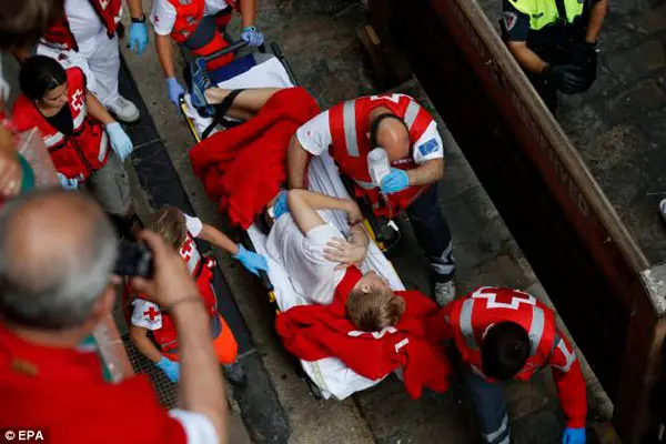 Emergência: A Cruz Vermelha transporta um corredor na maca para receber tratamento após ter sido chifrado. (Foto: Daily Mail)